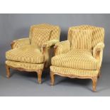 A pair of French walnut show frame armchairs upholstered in gold striped material raised on cabriole