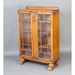 An Art Deco light oak display cabinet with raised back, interior fitted adjustable shelves