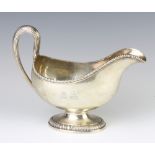 A George III silver sauce boat with egg and dart rim and simple scroll handle, London 1773, maker
