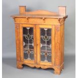 An Art Nouveau oak display cabinet with raised back fitted a shelf, the shelved interior enclosed by