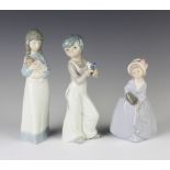 A Nao figure of a girl holding a puppy 23cm, a boy holding a bird 22cm and a Spanish figure of a