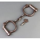 A pair of Warranted Rough, Darby style, police handcuffs complete with key, marked Warranted Rough