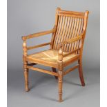 An Edwardian Arts and Crafts mahogany stick and rail back carver chair with woven rush seat,