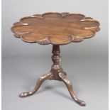 A George III shaped circular mahogany supper table with scallop edge, raised on a turned column