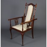 An Edwardian inlaid mahogany open arm reclining chair upholstered in green material, raised on