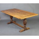 An elm 17th Century style refectory dining table with plank top, raised on cup and cover supports