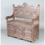 A Victorian heavily carved oak settle, the panelled back with bobbin turned decoration, the seat