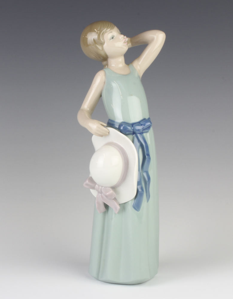 A Lladro figure of a girl holding her hat 5010 25cm