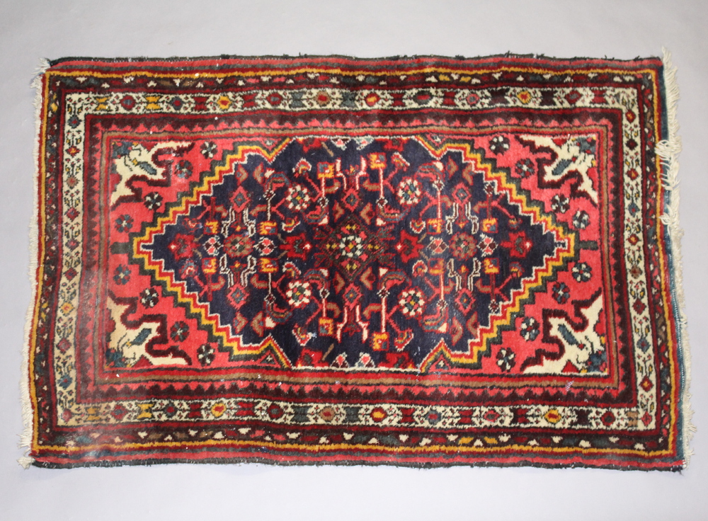 A Persian blue and red ground rug with central medallion 119cm x 78cm Light water marks and signs of