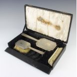 A silver Art Deco 3 piece brush set comprising hand mirror, hair brush and clothes brush cased