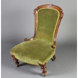 A Victorian mahogany show frame nursing chair upholstered in green material, raised on turned