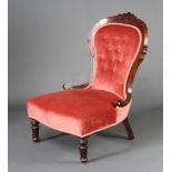 A Victorian mahogany framed nursing chair upholstered in pink buttoned dralon, raised on turned