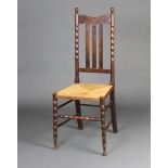 An Edwardian turned beech stick and rail back chair with woven rush seat and bobbin turned stretcher