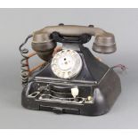 A black Bakelite telephone, the base incorporating a switchboard panel marked exchange, extension,