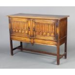 An Ipswich style carved light oak dresser base with cupboard enclosed by linen fold panelled