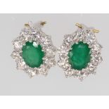 A pair of 18ct yellow gold oval emerald and diamond cluster earrings, the emeralds 3.6ct, the