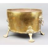 An oval planished brass twin handled planter with lion mask handles and paw feet 30cm h x 42cm w x