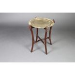 A Chinese circular brass and hardwood folding occasional table raised on outswept supports with