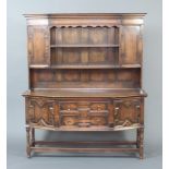 A 1920's Jacobean style oak dresser with moulded cornice, the upper section fitted 2 shelves flanked