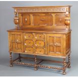 A 1930's light oak Jacobean style carved sideboard with raised back, fitted 3 drawers flanked by a