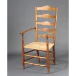 An Edwardian elm ladder back carver chair with woven rush seat, raised on turned supports