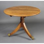 A Regency style circular light oak breakfast table raised on a turned column and tripod base with