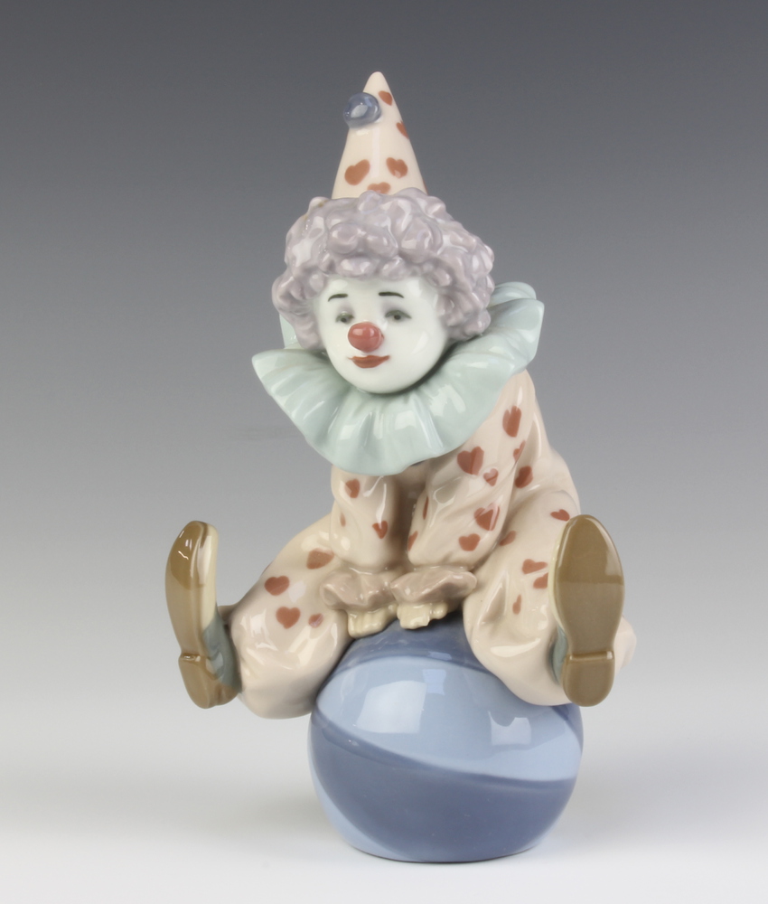 A Lladro figure of a clown sitting on a ball 5813 17cm