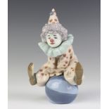 A Lladro figure of a clown sitting on a ball 5813 17cm