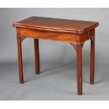 A Georgian mahogany card table of serpentine outline, pierced frets to the sides, raised on square