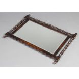 A 1930's rectangular bevelled plate wall mirror contained in a carved and pierced oak frame with