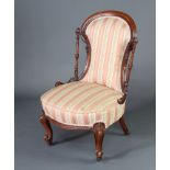 A Victorian walnut show frame nursing chair upholstered in pink and gold Regency stripe, raised on