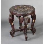 A circular carved Indian ebony occasional table raised on 4 elephant supports with X framed