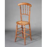 A child's 19th Century mahogany stick and bar back training chair with woven rush seat, raised on