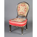 A Victorian carved and ebonised nursing chair, the seat and back upholstered in Berlin woolwork
