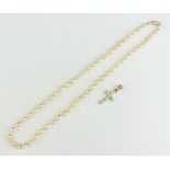 A string of cultured pearls with a gold clasp and a gold gem set cross pendant