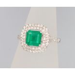 An 18ct white gold emerald and diamond cluster ring, the centre cushion cut stone approx. 1.24ct