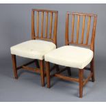 A pair of 19th Century mahogany stick and rail back dining chairs with over stuffed seats, raised on