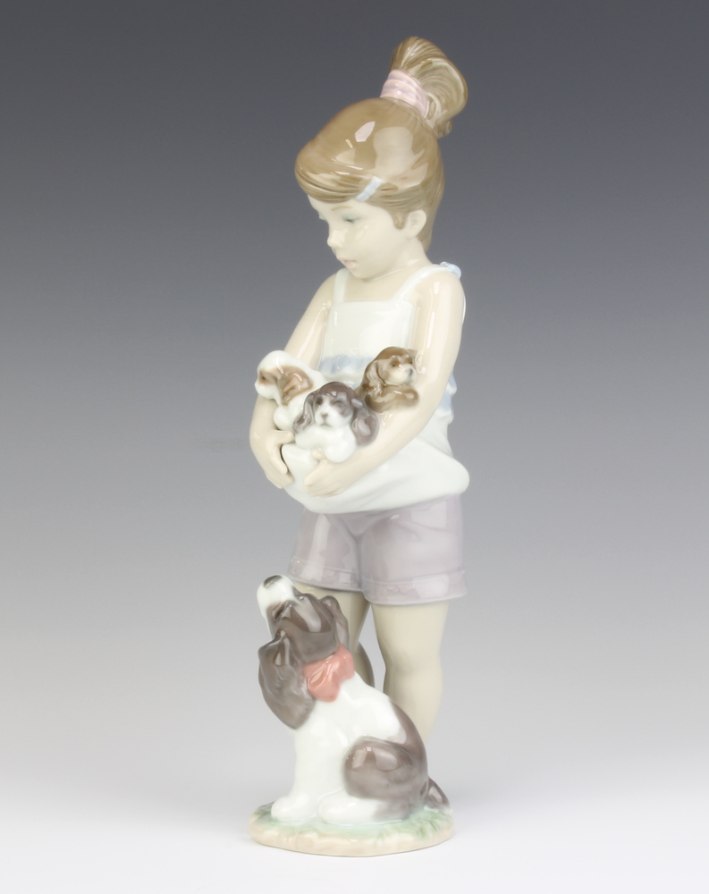 A Lladro figure of a young girl holding puppies with a dog at her feet - Annual piece 2013, 23cm