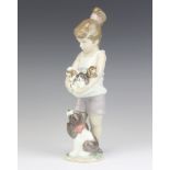 A Lladro figure of a young girl holding puppies with a dog at her feet - Annual piece 2013, 23cm