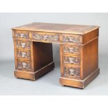 A Victorian carved oak kneehole pedestal desk with inset writing surface above 1 long and 8 short