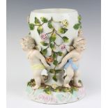 A Dresden style oil lamp, the base supported by cherubs 25cm h The flowers are chipped and the