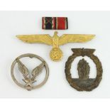 A German Nazi gilt metal cap badge in the form of an eagle, two other badges and a ribbon bar