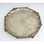 A silver salver with shell and scroll rim, raised on scroll feet with engraved signatures, London