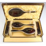 A silver and tortoiseshell plique a jour dressing table set comprising two hair brushes, 2 clothes