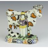 An 18th Century faience figure group of cow and herdsman, raised on an oval base 13cm x 14cm x 7.5cm