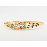 An 18ct yellow gold diamond, ruby, sapphire and emerald bangle, 11.4 grams