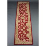 A red and gold patterned machine made floral runner 272cm x 79cm