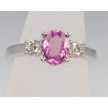 An 18ct white gold oval pink sapphire and diamond ring, the centre stone 1.5ct, the diamonds 0.