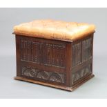 A carved oak ottoman with linen fold decoration and hinged lid, the seat upholstered in brown