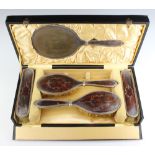 A silver and tortoiseshell plique a jour dressing table set comprising 2 hair brushes, 2 clothes